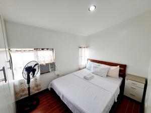 Schlafzimmer mit einem weißen Bett und einem Ventilator in der Unterkunft Furnished House in Calapan City Subdivision near ROBINSONS Mall L33 in Calapan