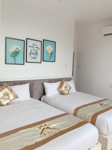 2 Betten in einem Zimmer mit 3 Bildern an der Wand in der Unterkunft Lagi Sunrise Hotel in La Gi