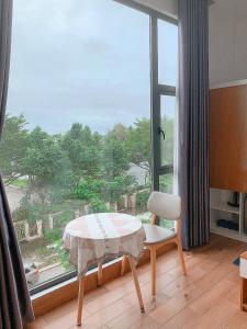 Zimmer mit einem Tisch, einem Stuhl und einem großen Fenster in der Unterkunft Lagi Sunrise Hotel in La Gi