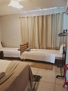 1 dormitorio con 2 camas y cortina en Pousada Luar en Chapada dos Guimarães