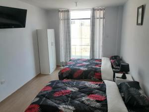 a bedroom with two beds and a couch and a window at Alemar's House in Nazca