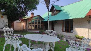 uma mesa e cadeiras em frente a uma casa em Cabañas Los Cactus em San Miguel Regla