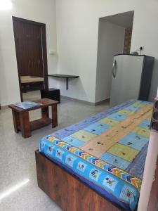 a bedroom with a bed and a table and a refrigerator at Shree 53 1BHK in Bangalore