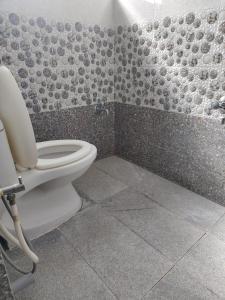 a bathroom with a toilet and a tile wall at Shree 53 1BHK in Bangalore