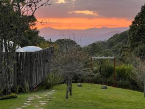 a garden with a fence and a view of the mountains at La Estela Bubble Glamping in Mazamitla