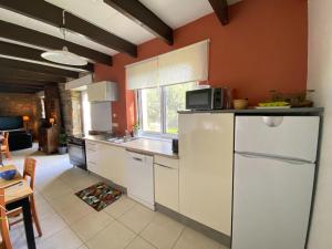 uma cozinha com paredes cor de laranja e armários brancos e um balcão em Gite in Ploneour-Lanvern em Plonéour-Lanvern