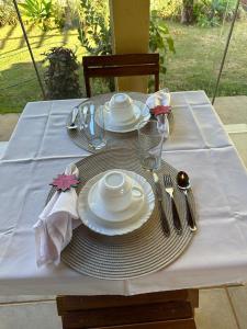 una mesa con platos y cubiertos de plata sobre un mantel blanco en Pousada Luar en Chapada dos Guimarães