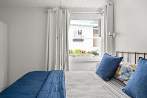 um quarto com uma cama com almofadas azuis e uma janela em The Big House em Bundeena