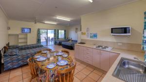 a kitchen and a living room with a table and chairs at Gone Fishin Holiday Units in Karumba