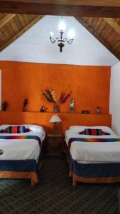 2 Betten in einem Zimmer mit orangefarbenen Wänden in der Unterkunft Cabañas Los Cactus in San Miguel Regla
