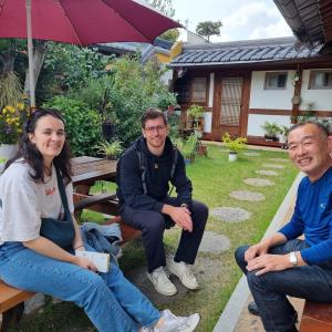 a group of people sitting on a bench in front of a house at Hanok Dream in Jeonju