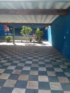 een lege patio met een blauwe muur en een geruite vloer bij Casa aconchegante de praia in Itanhaém