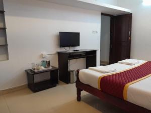 a hotel room with a bed and a television at Royal Serene Villas in Ooty