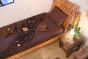 a bed with brown sheets and a table in a room at Jambiani Café & Bungalow in Jambiani