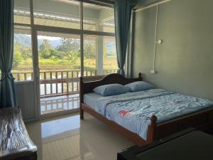 a bedroom with a bed and a large window at มองภู โฮมสเตย์ in Ban Fang