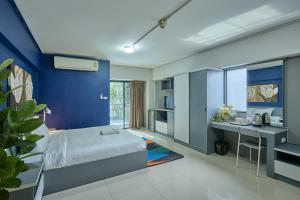a bedroom with blue walls and a bed and a desk at The Trust Ville in Bangkok