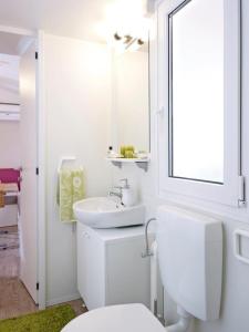 biała łazienka z toaletą i umywalką w obiekcie Sárvár Fürdő Mobilházak w Sárvárze