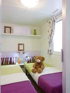 a teddy bear sitting on two beds in a room at Sárvár Fürdő Mobilházak in Sárvár