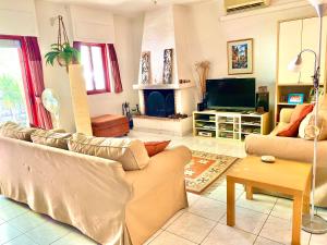 a living room with a couch and a tv at 2 Bedroom, Sea Side Retreat Saronida in Saronida