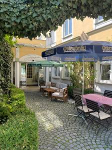 un patio con tavolo, sedie e ombrelloni di Hotel Jungbräu a Abensberg
