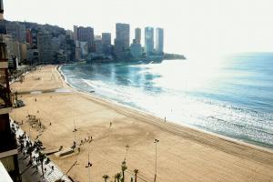 a beach with people on it next to the ocean at Apartamentos Torre Levante - Arca Rent in Benidorm