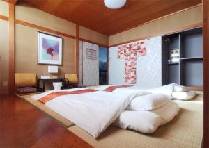 um quarto com uma cama grande e lençóis brancos em 心遊亭ー敬華の間Shin Yu Tei em Kanazawa