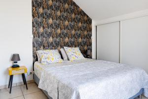 a bedroom with a bed and a wall with a bird wallpaper at Saint-leu Réunion centre ville T3 Duplex meublé in Saint-Leu