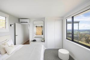 um quarto com uma cama branca e uma grande janela em The Bella Vista by Mt Bellevue em Myrrhee