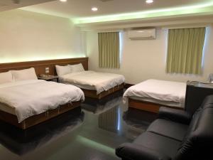 花蓮市にある奇萊大飯店 Chuline Hotelのベッド2台とソファが備わるホテルルームです。