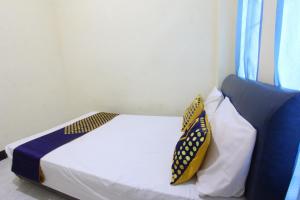 een slaapkamer met een bed met 2 kussens erop bij OYO Life 93157 Kos Kaloka in Tanjung