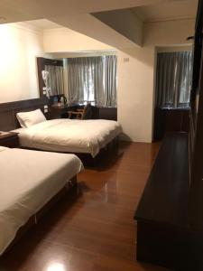 a hotel room with two beds and a desk at 奇萊大飯店 Chuline Hotel in Hualien City