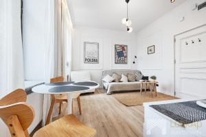 een witte woonkamer met een tafel en een bank bij Kilińskiego 33 Street I by LookAp in Łódź
