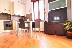 a kitchen with a table with chairs and a flat screen tv at Luxury Verona Apartment City Centre in Verona