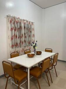 a white table with chairs and a vase of flowers on it at Ocean and mountain view house in Mabini