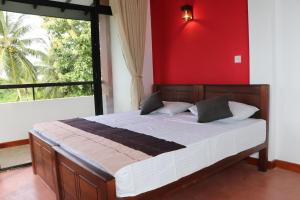 ein Schlafzimmer mit einem Bett mit einer roten Wand und einem Fenster in der Unterkunft Kadupitioya Bungalow 