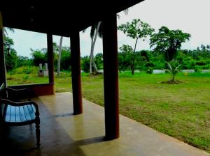 eine Bank auf einer Veranda auf einem Feld in der Unterkunft Kadupitioya Bungalow 