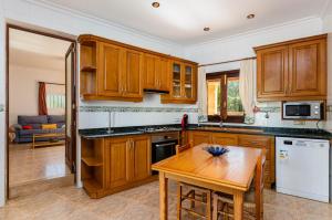 uma cozinha com armários de madeira e uma mesa de madeira em YourHouse Es Pleto Villa em Lloret de Vistalegre