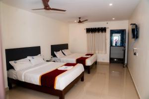 a bedroom with two beds and a ceiling fan at Hotel Sitar Grand in Tirupati