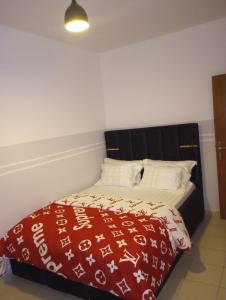 a bedroom with a bed with a red and white blanket at ANGELA HOME in Douala