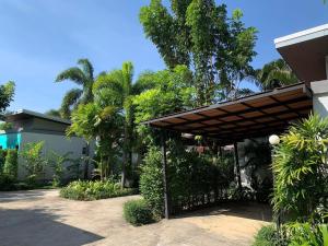 a house with a wooden pergola and palm trees at ยูสีเกด รีสอร์ท in Si Sa Ket