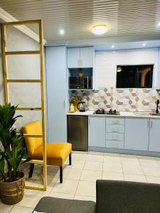 een keuken met blauwe kasten en een gele stoel bij Modern studio apartments in Secunda
