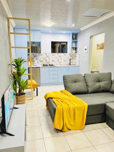 een woonkamer met een bank en een gele deken bij Modern studio apartments in Secunda
