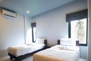 two beds in a room with a window at ยูสีเกด รีสอร์ท in Si Sa Ket