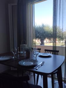 a dining room table with plates and glasses and a window at Olive Garden Studios & Apartments in Acharavi