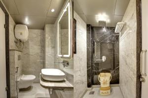 a bathroom with a toilet and a sink and a shower at Hotel Kaca Inn-by Haveliya Hotels in New Delhi