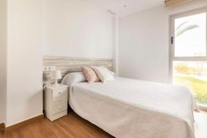 ein weißes Schlafzimmer mit einem Bett und einem Fenster in der Unterkunft Orilla del mar in Oliva