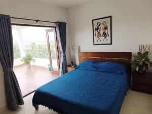 a bedroom with a blue bed and a balcony at Casa Do Mundo - Your Holiday Home in Porvorim
