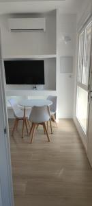 Cette chambre blanche dispose d'une table, de chaises et d'une télévision. dans l'établissement Precioso apartamento de diseño para 4-6 personas VT-55212-V, à Valence