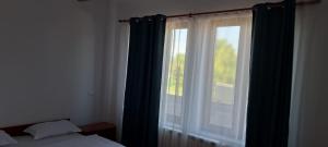 a bedroom with a window with blue curtains at Casa Francesca in Comăneşti