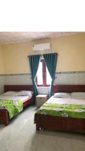 a bedroom with two beds and a window at San Vuon Guesthouse in Mui Ne